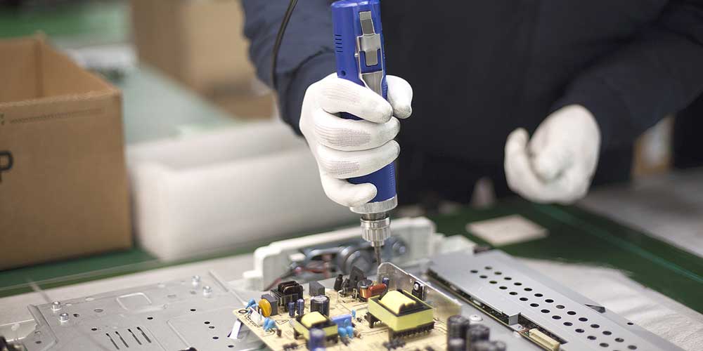 Photo of a man using electrical drill on circuitboard